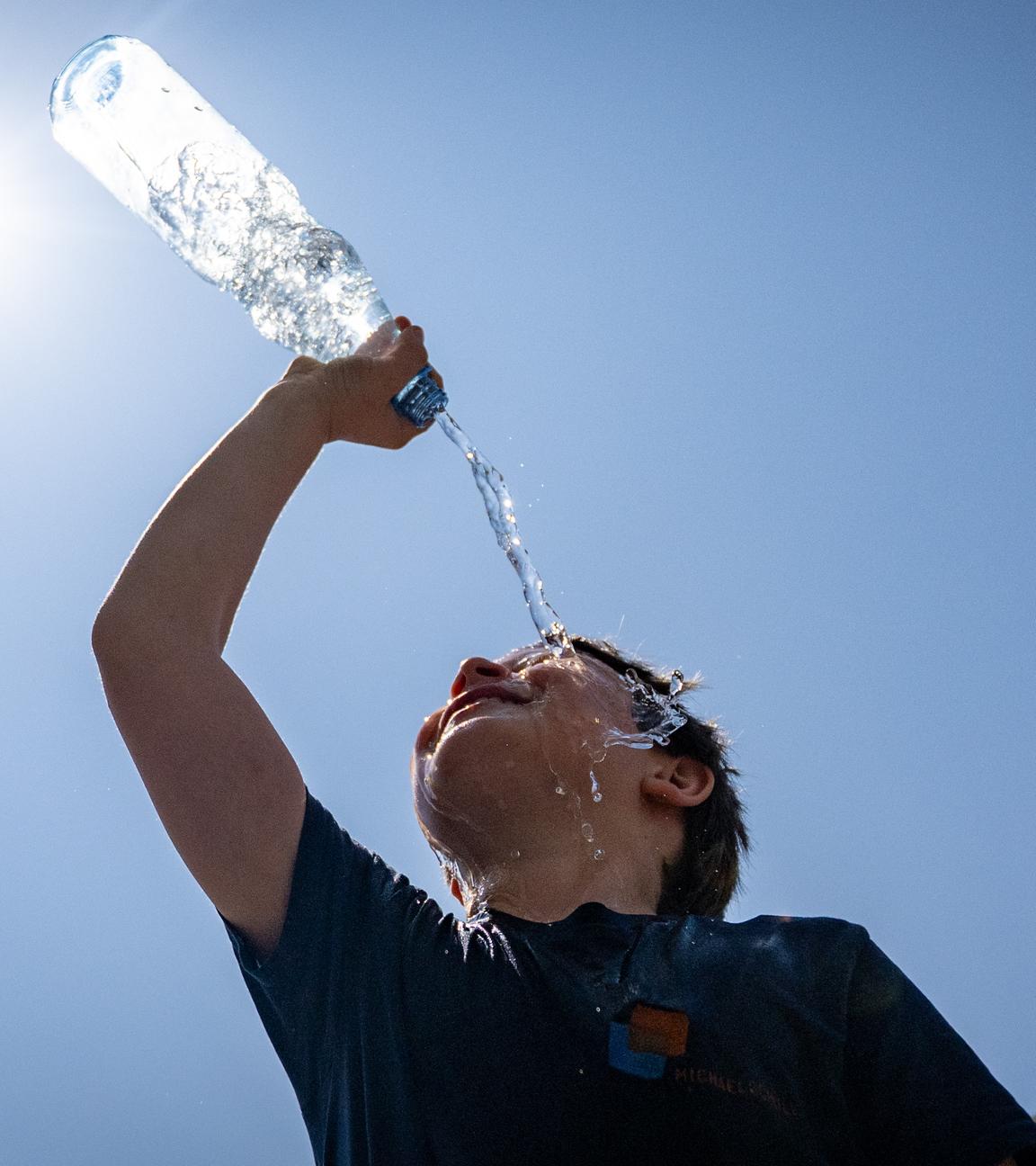 Ein Junge schüttet Wasser aus einer Flasche über sich aus