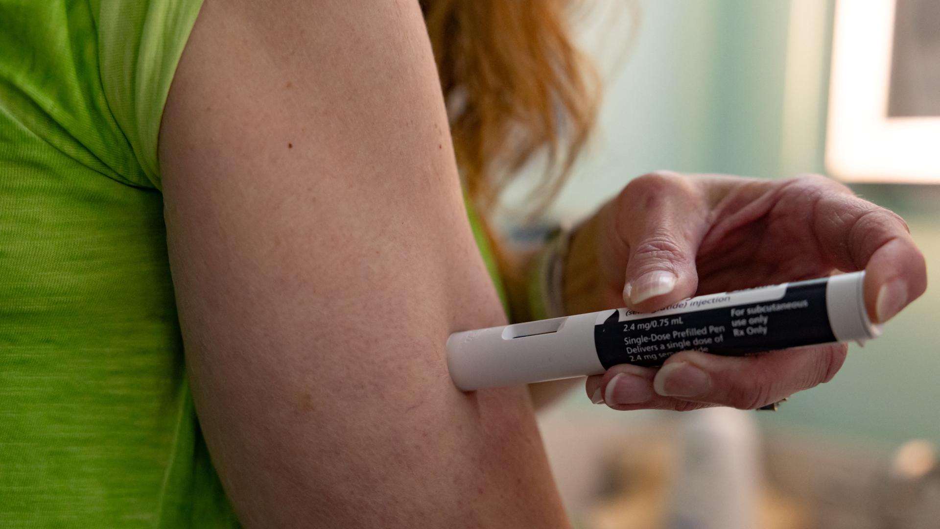 Eine Frau wendet eine Abnehmspritze an ihrem Arm an.