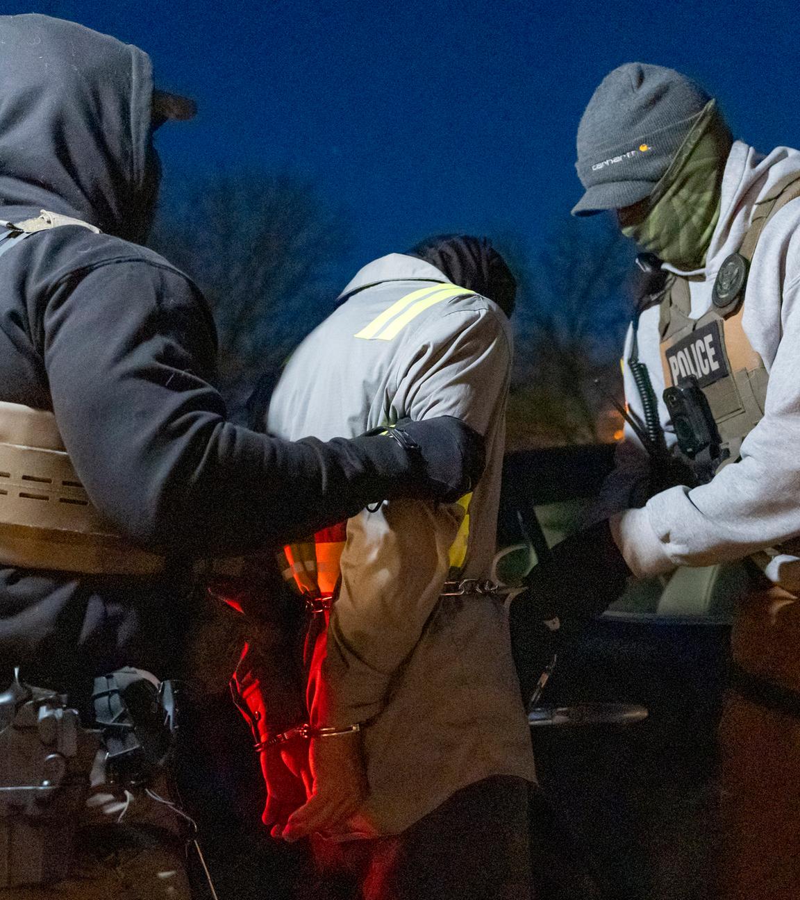 Archiv: Beamte der US-Einwanderungs- und Zollbehörde verwenden eine Kette, um eine festgenommene Person mit Handschellen an der Vorderseite bequemer festhalten zu können. 