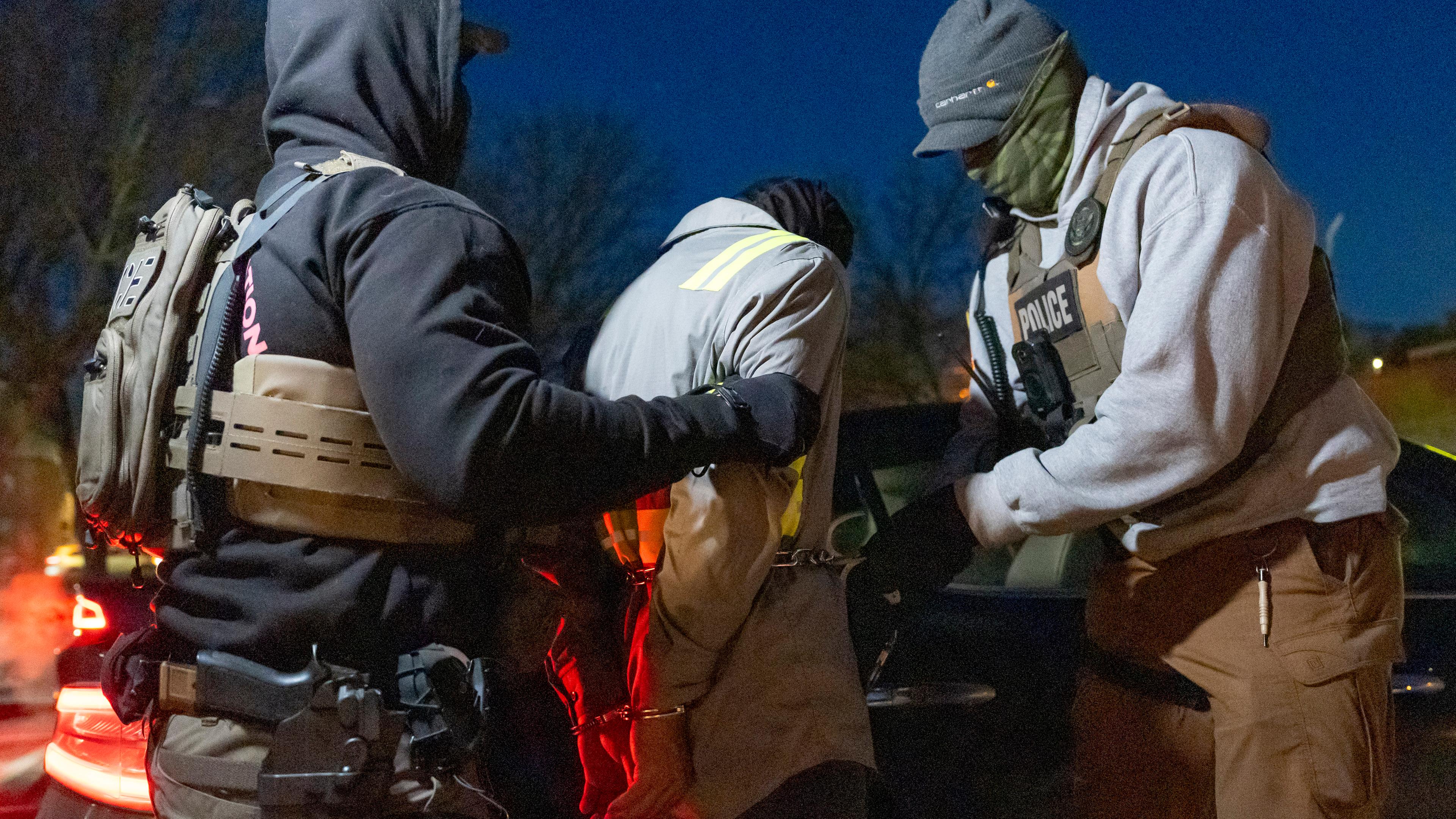 Archiv: Beamte der US-Einwanderungs- und Zollbehörde verwenden eine Kette, um eine festgenommene Person mit Handschellen an der Vorderseite bequemer festhalten zu können. 