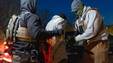 Archiv: Beamte der US-Einwanderungs- und Zollbehörde verwenden eine Kette, um eine festgenommene Person mit Handschellen an der Vorderseite bequemer festhalten zu können. 