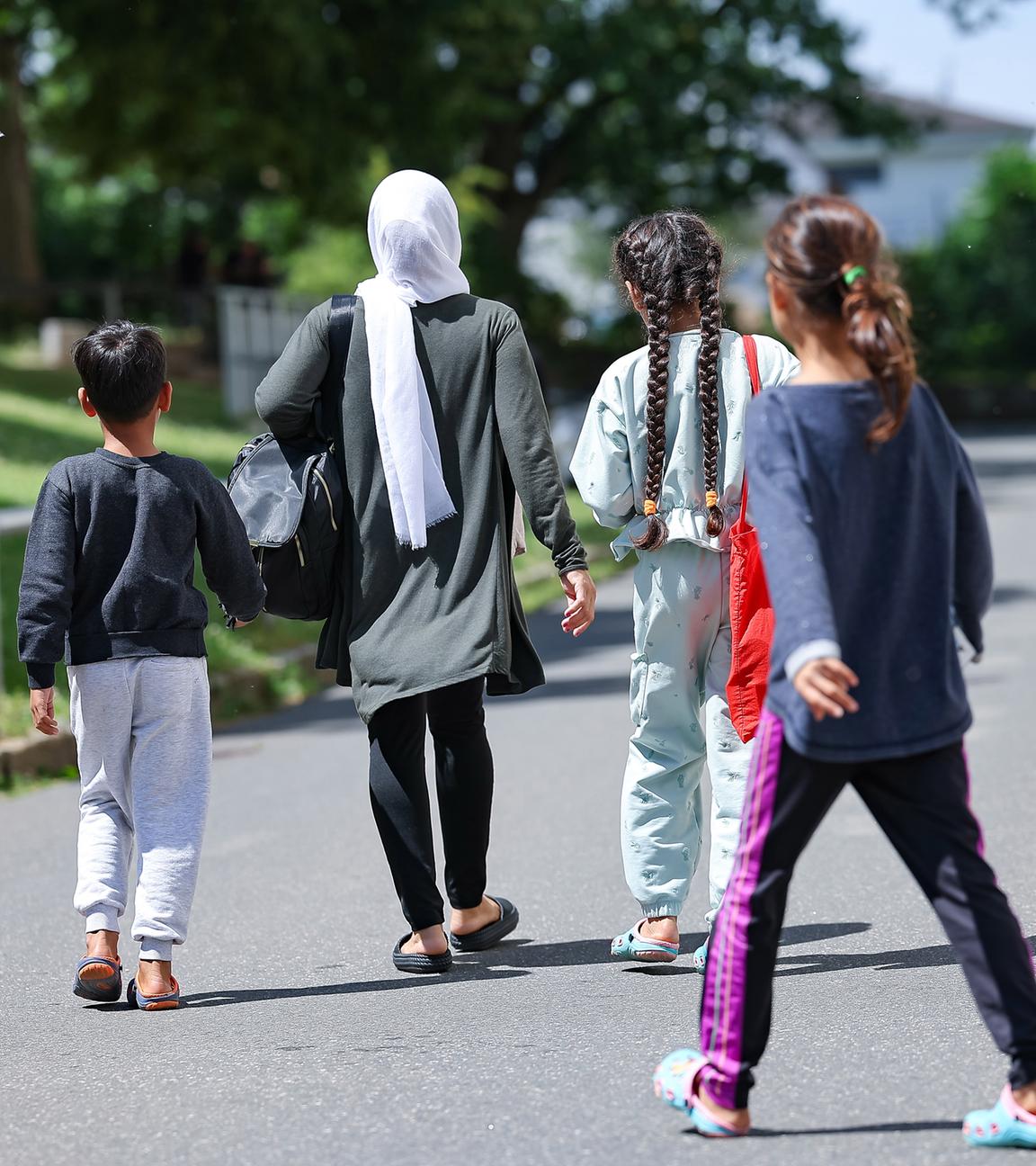 18.06.2024, Bayern, Zirndorf: Eine Frau geht mit drei Kindern in der Zentralen Aufnahmeeinrichtung für Asylbewerber in Bayern über das Gelände. 