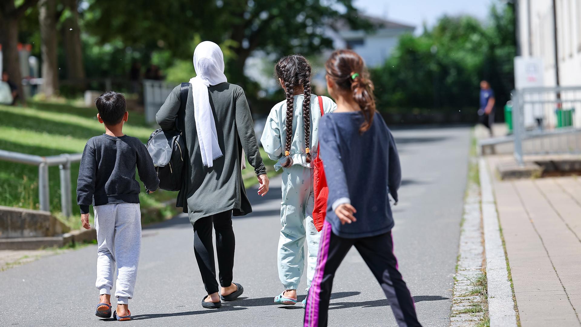 18.06.2024, Bayern, Zirndorf: Eine Frau geht mit drei Kindern in der Zentralen Aufnahmeeinrichtung für Asylbewerber in Bayern über das Gelände. 