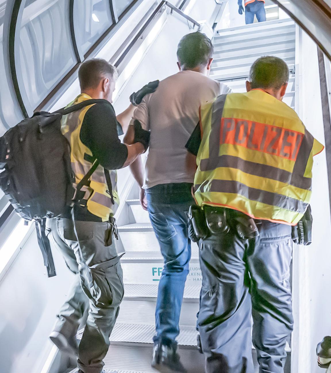 Polizeibeamte begleiten einen abgelehnten Asylbewerber auf dem Flughafen Leipzig-Halle in ein Charterflugzeug. (Archiv)