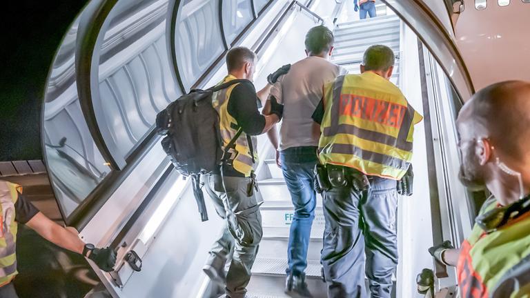 Polizeibeamte begleiten einen abgelehnten Asylbewerber auf dem Flughafen Leipzig-Halle in ein Charterflugzeug. (Archiv)