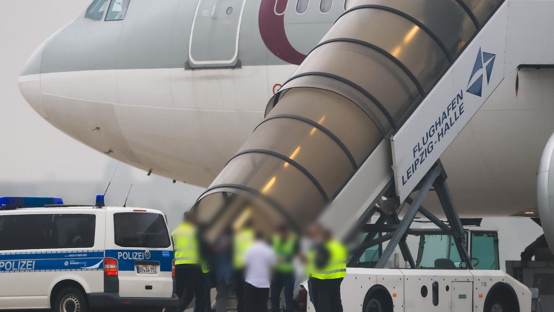 Menschen besteigen ein Flugzeug der Qatar Airways, vor dem Fahrzeuge der Bundespolizei stehen auf dem Vorfeld am Flughafen Leipzig/Halle.