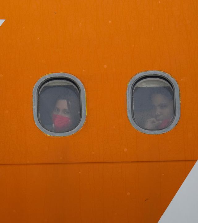 Aus den Vereinigten Staaten abgeschobene venezolanische Migranten schauen nach der Landung aus den Bullaugen ihres Flugzeugs.
