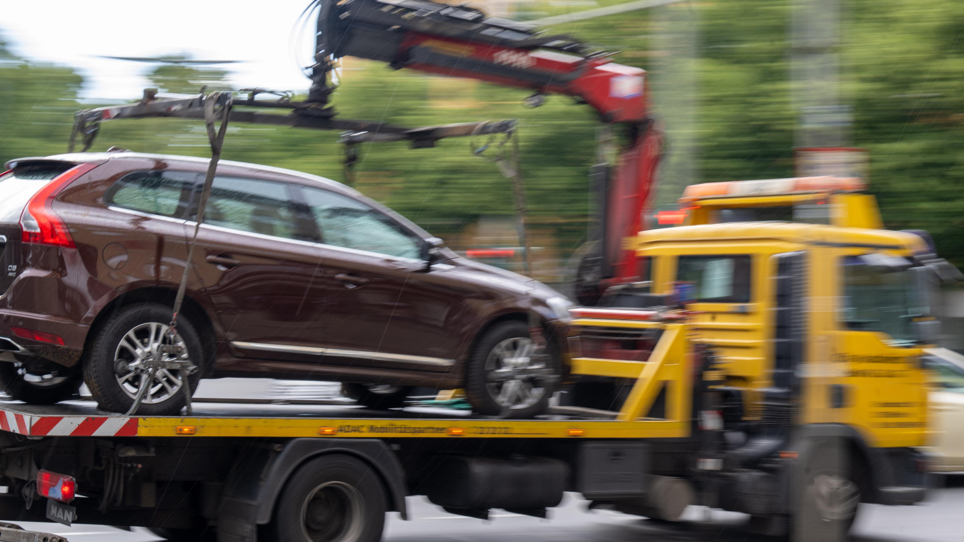 Ein Abschleppwagen mit einem Volvo fährt über eine Straße.
