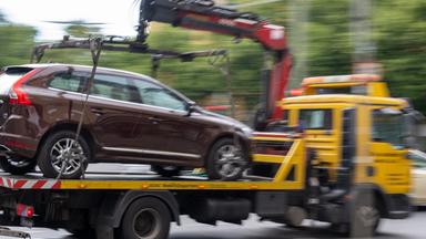 Ein Abschleppwagen mit einem Volvo fährt über eine Straße.