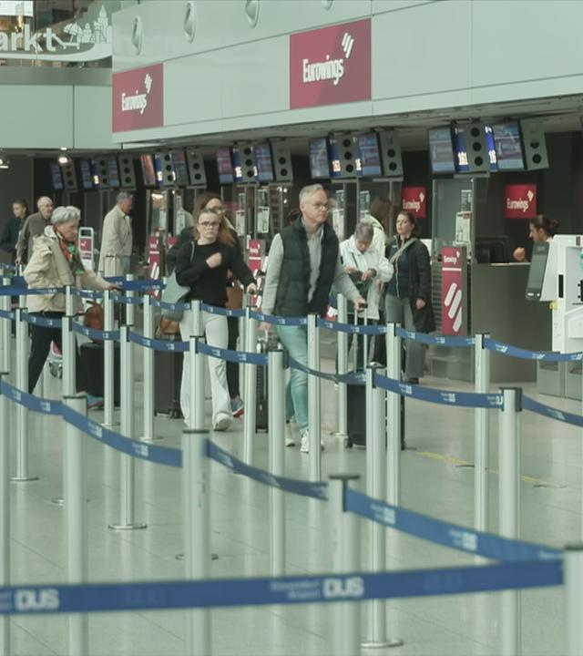 Reisende am Flughafen vor Eurowings-Schalter