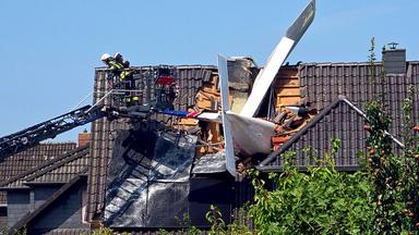 Ein abgestürztes Leichtflugzeug steckt im Dach eines Hauses.