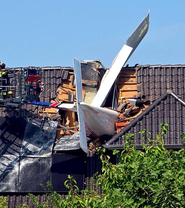 Ein abgestürztes Leichtflugzeug steckt im Dach eines Hauses.