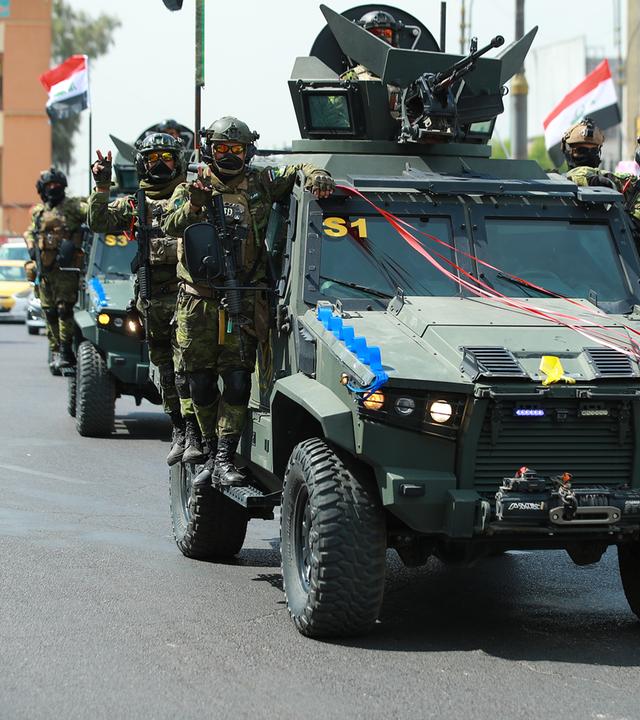 rak, Bagdad: Irakische Soldaten zeigen das Friedenszeichen bei einem Konvoi von Sicherheitsfahrzeugen durch die irakische Hauptstadt, während der Feierlichkeiten zum Tag der nationalen Souveränität des Irak und zum Abzug der US-Truppen.