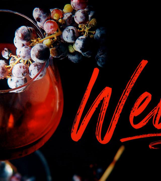 Weinglas mit roten Weintrauben und Titelgrafik "Wein"