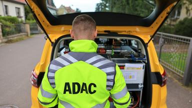 Sachsen, Leipzig: Ein ADAC-Pannenhelfer steht nach einer Pannenhilfe am Kofferraum seines Fahrzeugs