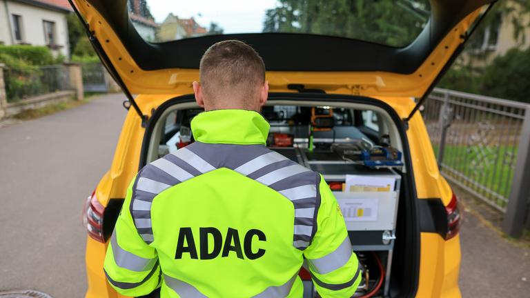 Sachsen, Leipzig: Ein ADAC-Pannenhelfer steht nach einer Pannenhilfe am Kofferraum seines Fahrzeugs