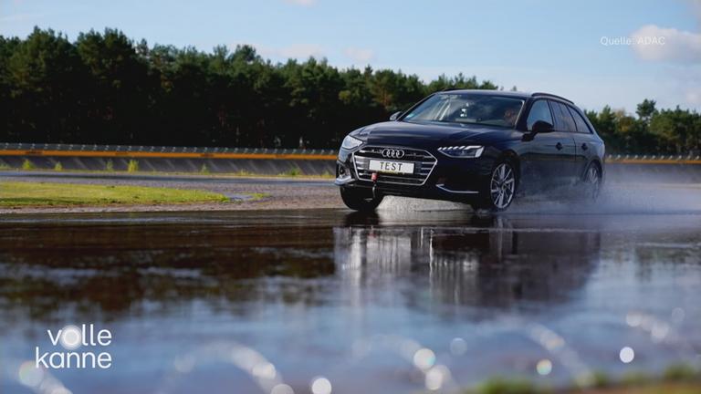 Ein schwarzes Auto fährt durch eine Pfütze.