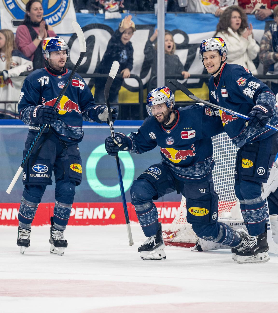 Die Eishockeyspieler Adam Brooks (links) und Alberts Smits (rechts) freuen sich mit Tobias Rieder (Mitte) der Red Bull München über dessen Tor zum 5:2 gegen ERC Ingolstadt am 29.03.2026.