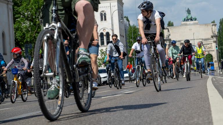18.05.2025, Bayern, München: Vor dem Siegestor fahren Radler über die Leopoldstraße.