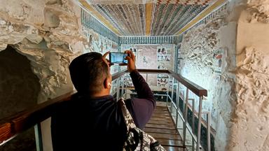  Ein Besucher fotografiert im Inneren des kürzlich restaurierten antiken Grabes des Amenhotep in der Nekropole von El-Khokha am Westufer des Nils in Luxor, Ägypten.