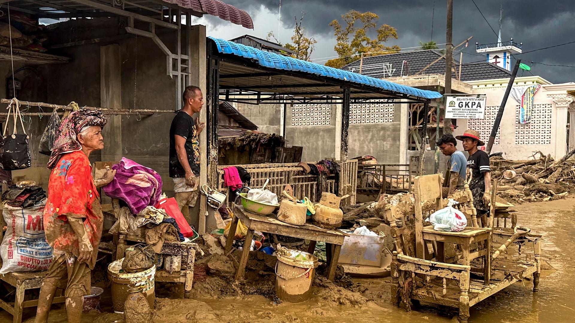 Von Sturzfluten betroffene Dorfbewohner reinigen am 05.12.2025 ihre Häuser und Habseligkeiten im Dorf Aek Ngadol im Regierungsbezirk Süd-Tapanuli in der Provinz Nord-Sumatra von Schlamm.
