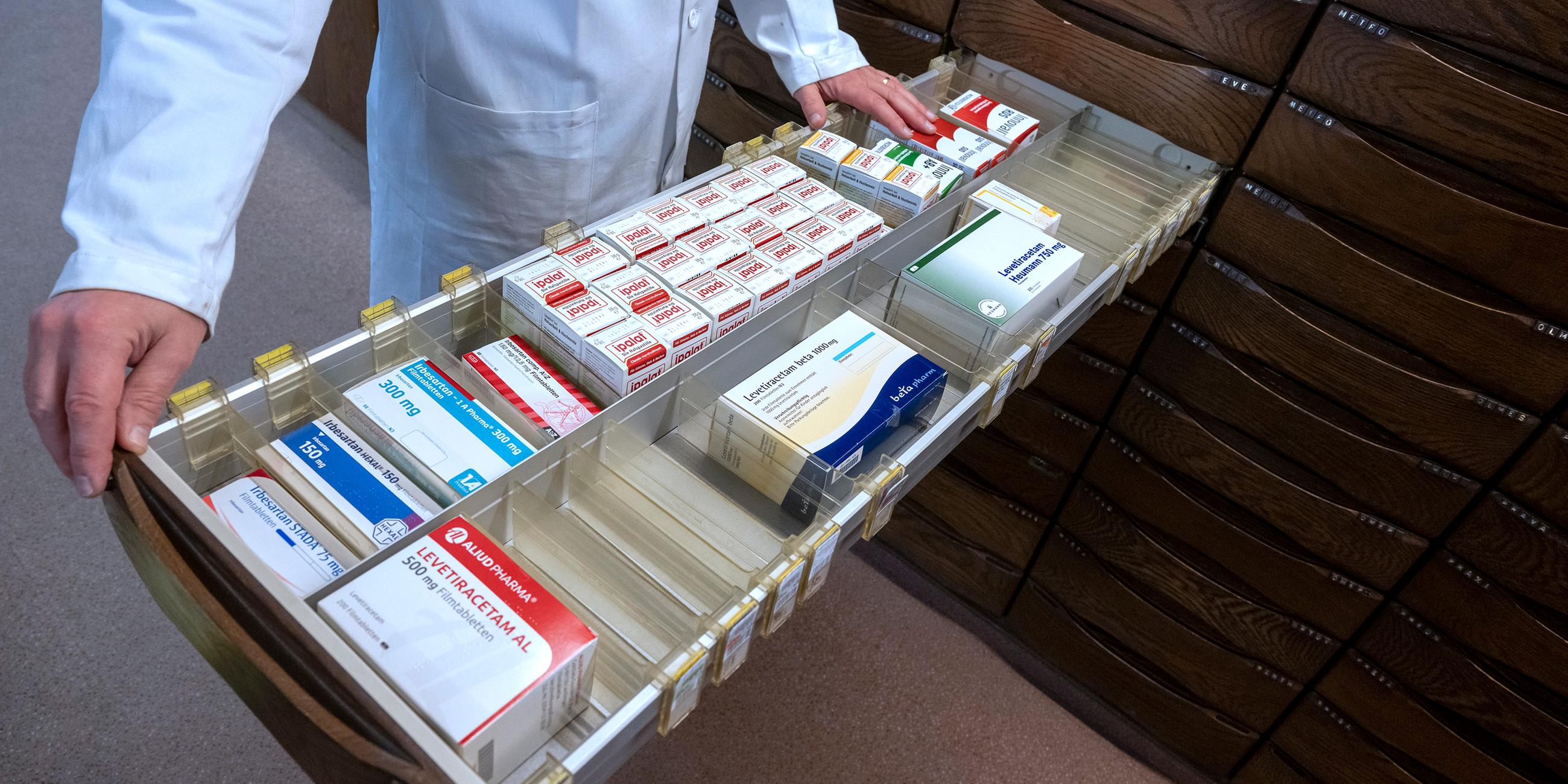 Ein Apotheker schaut in den Medikamentenschrank seiner Apotheke.