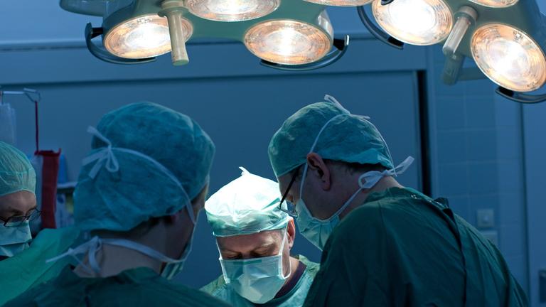 Ein Operation wird von Chirurgen unter OP-Licht durchgeführt.