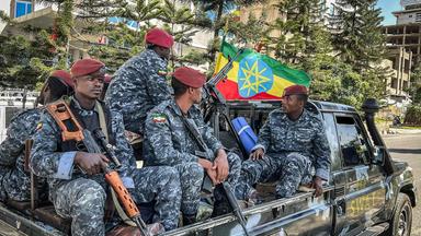 Bewaffnete Männer der Äthiopischen Staatspolizei (Ethiopian Federal Police) sitzen auf der Ladefläche eines Trucks, im Hintergrund weht die äthiopische Flagge.