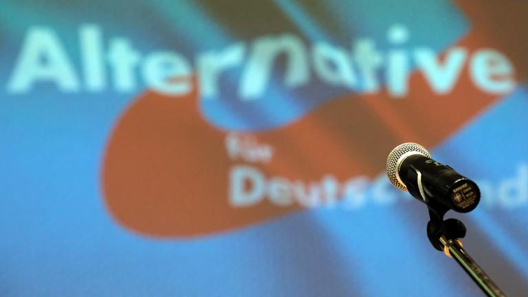 Archiv: Ein Mikrofon steht bei einem Parteitag der AfD auf der Bühne vor dem Partei-Logo