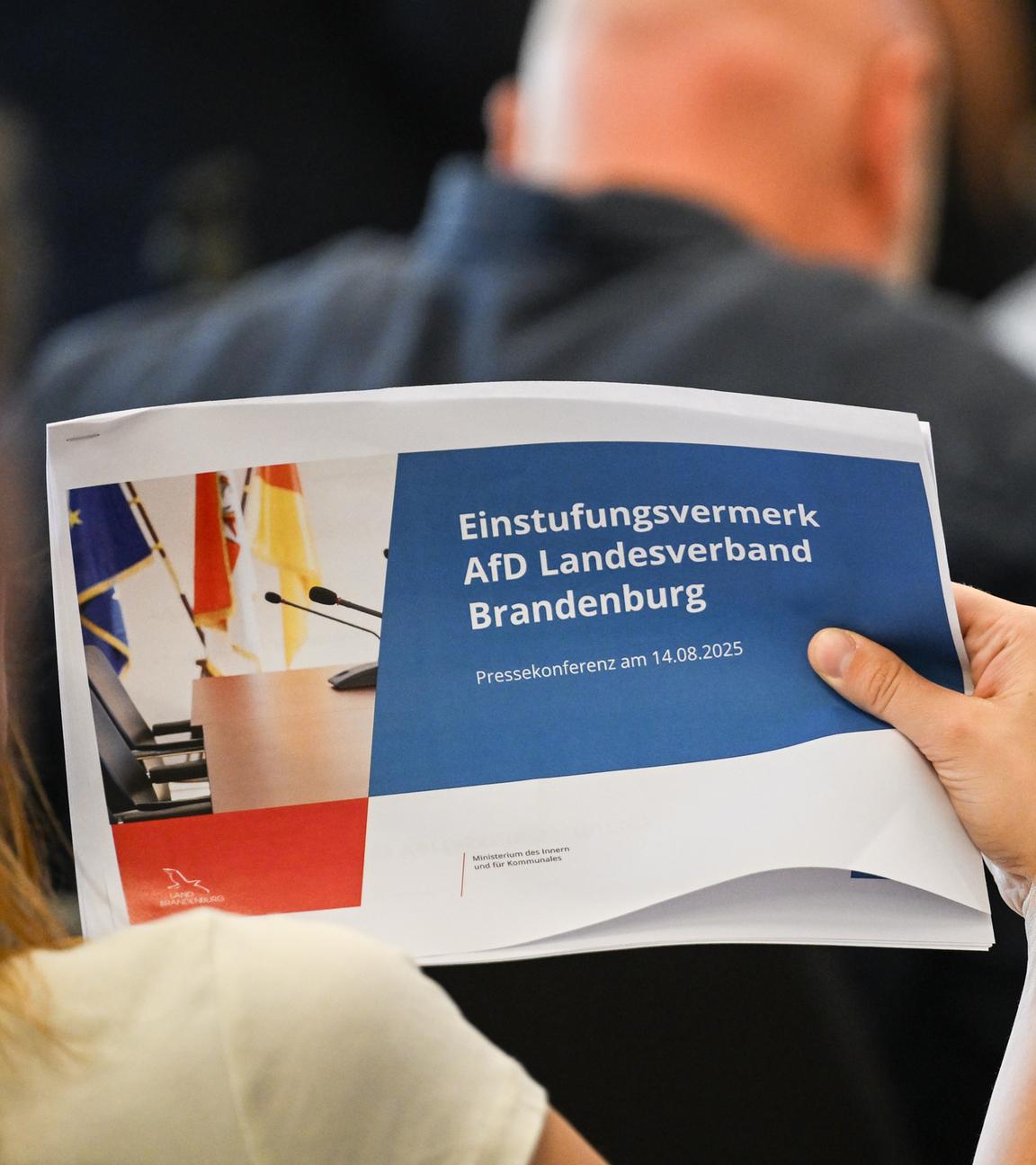 14.08.2025, Brandenburg, Potsdam: Eine Journalistin hält eine Ausgabe der Veröffentlichung eines Einstufungsvermerks zur AfD Brandenburg als rechtsextrem in der Hand.