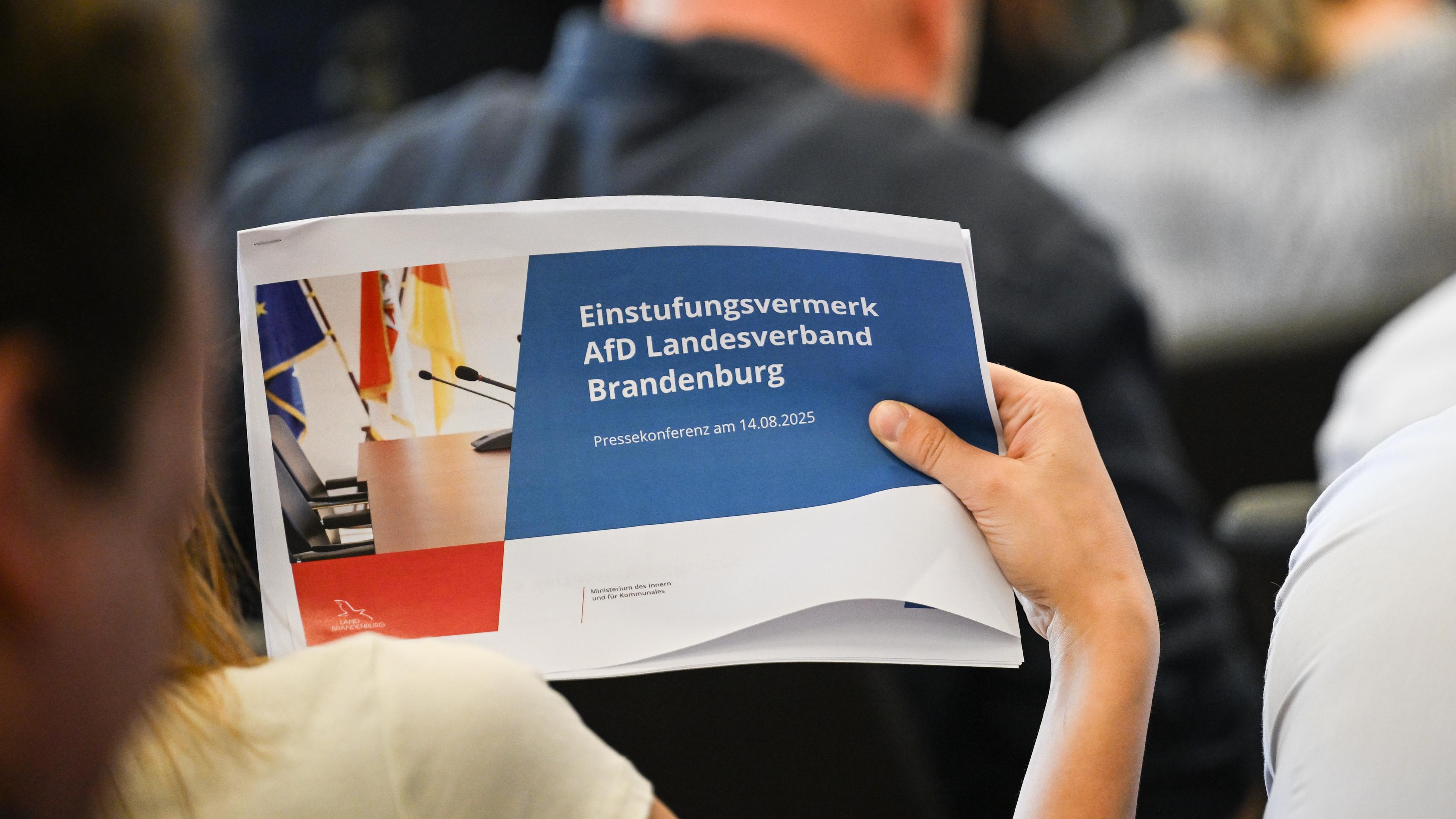 14.08.2025, Brandenburg, Potsdam: Eine Journalistin hält eine Ausgabe der Veröffentlichung eines Einstufungsvermerks zur AfD Brandenburg als rechtsextrem in der Hand.