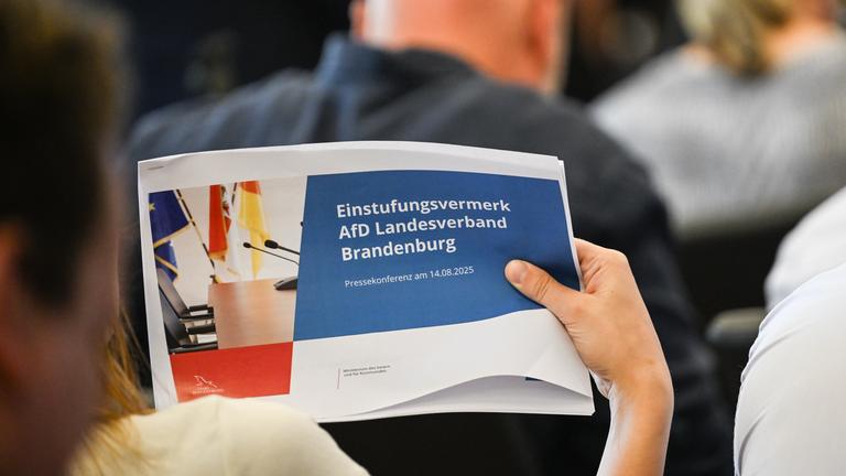 14.08.2025, Brandenburg, Potsdam: Eine Journalistin hält eine Ausgabe der Veröffentlichung eines Einstufungsvermerks zur AfD Brandenburg als rechtsextrem in der Hand.