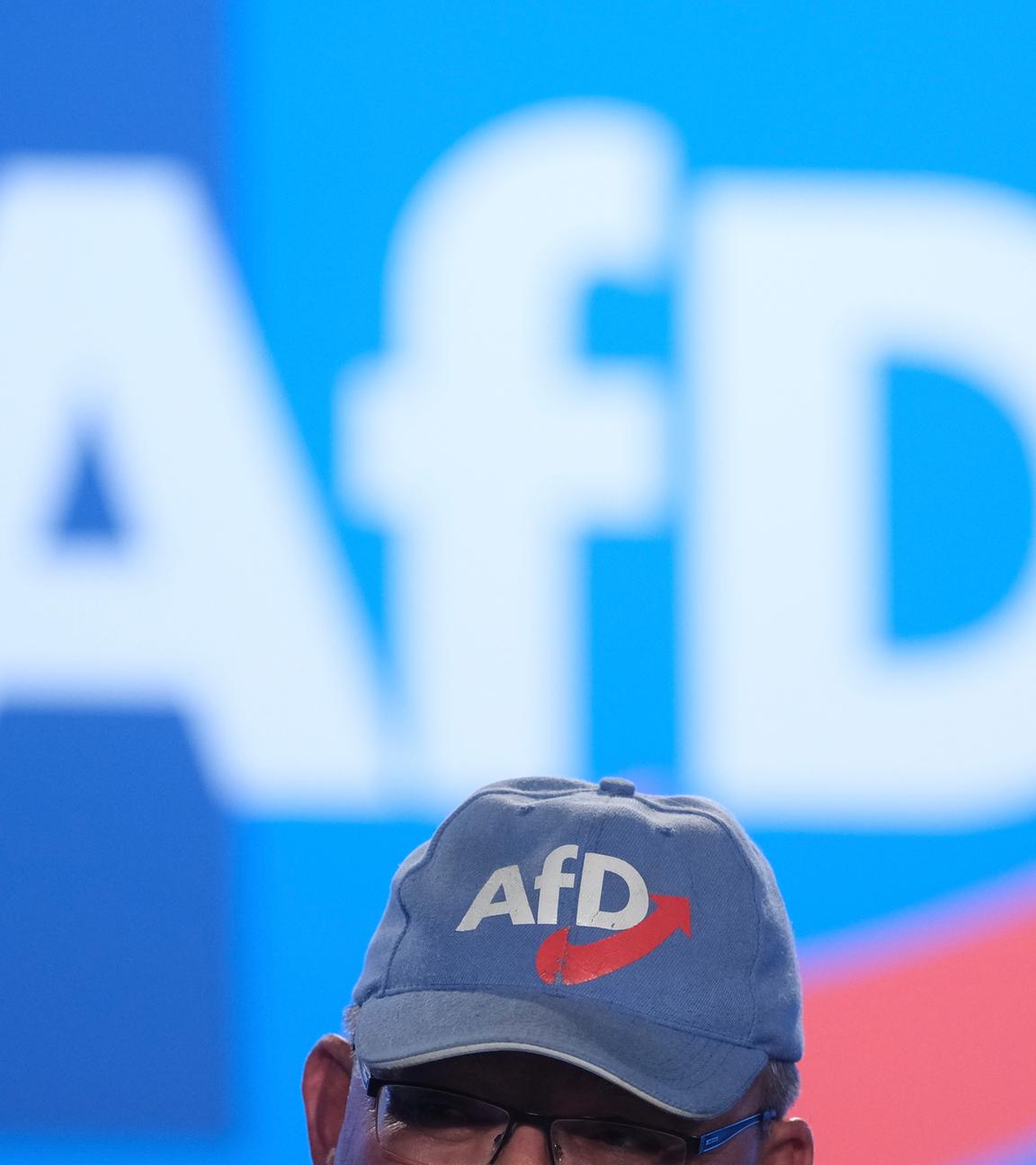 Eine AfD-Kappe vor einem großen Afd-Logo an der Wand