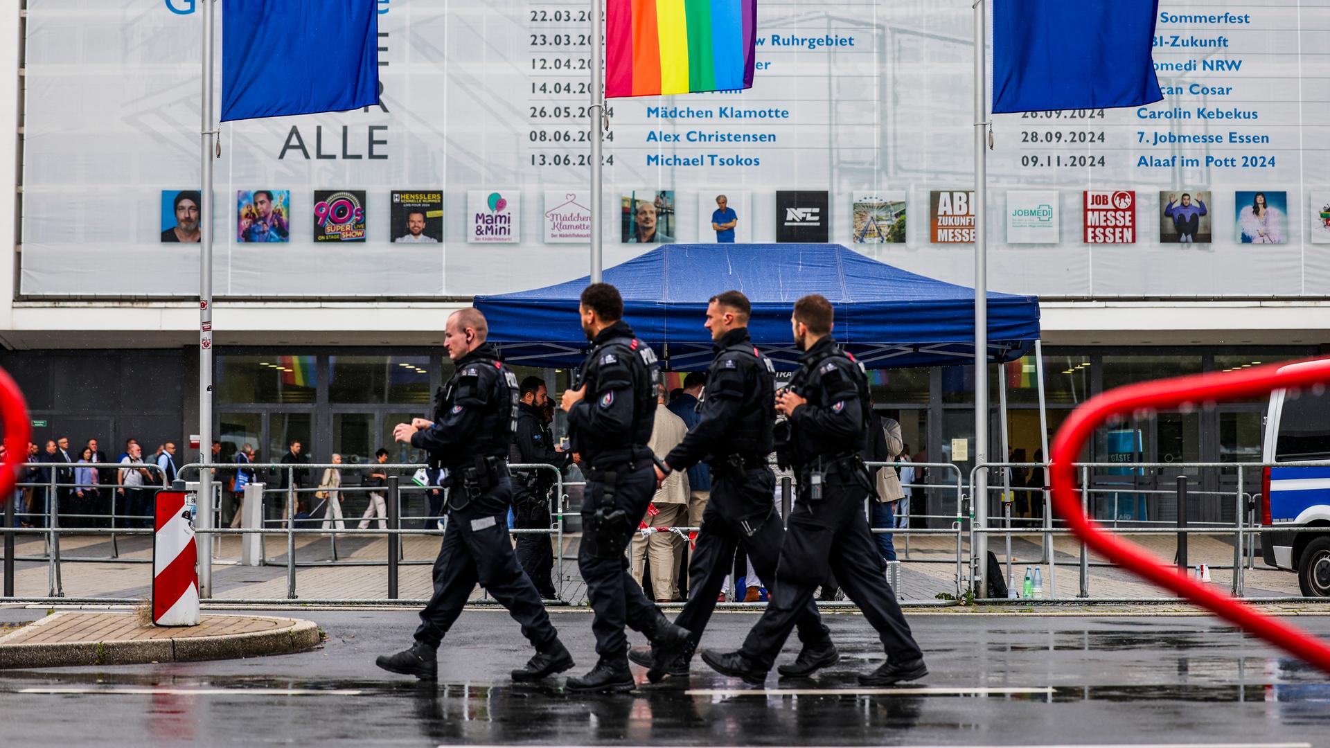  Polizeibeamte laufen im Regen vor der Grugahalle entlang am 30.06.2024.