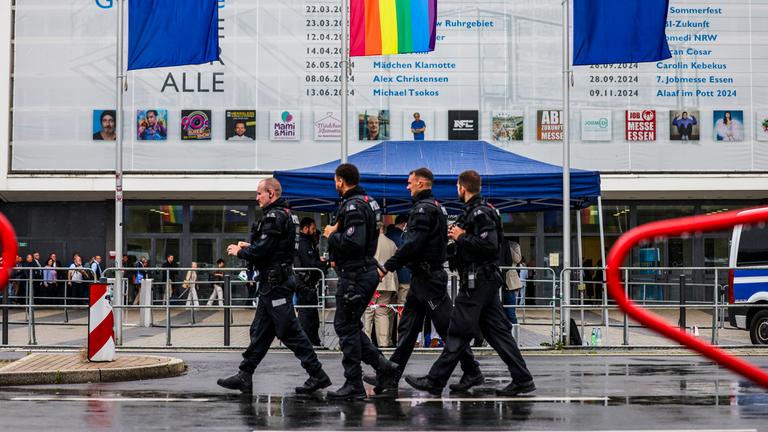  Polizeibeamte laufen im Regen vor der Grugahalle entlang am 30.06.2024.