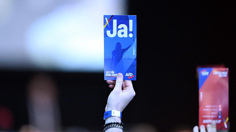 Eine Hand eines Delegierten auf dem AfD-Parteitag in Gießen hält eine Stimmkarte mit der Aufschrift "Ja!" in die Luft.