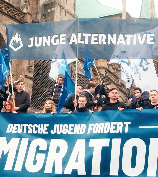 Demo "Junge Alternative", Teilnehmer mit Banner: "Deutsche Jugend fordert Remigration!"