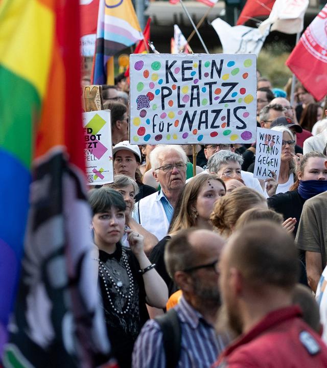 Teilnehmer einer Demonstration halten Schilder in die Luft.