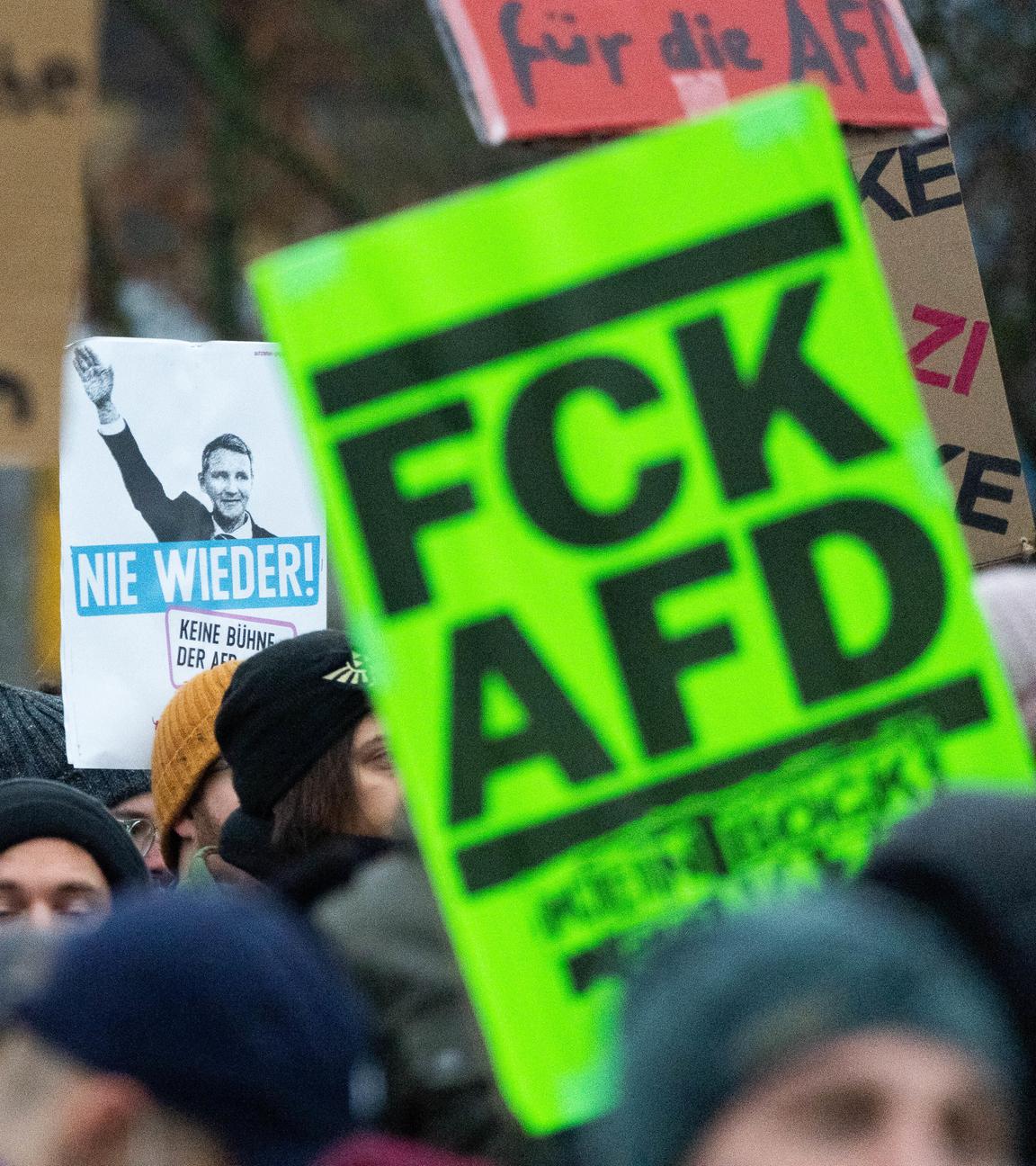 Menschen, die gegen die Jugendorganisation der Afd namens "Neue Generation" protestieren. Sie laufen und halten mehrere Plakate. 