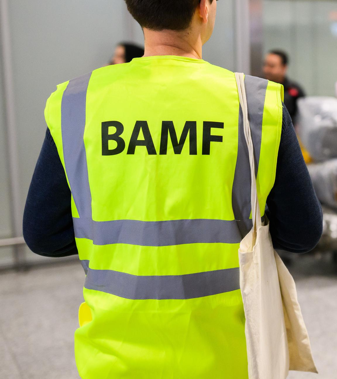 Ein Mitarbeiter vom BAMF Bundesamt für Migration und Flüchtlinge steht im Flughafen Hannover vor Afghaninnen und Afghanen aus den Bundesaufnahmeprogrammen. 