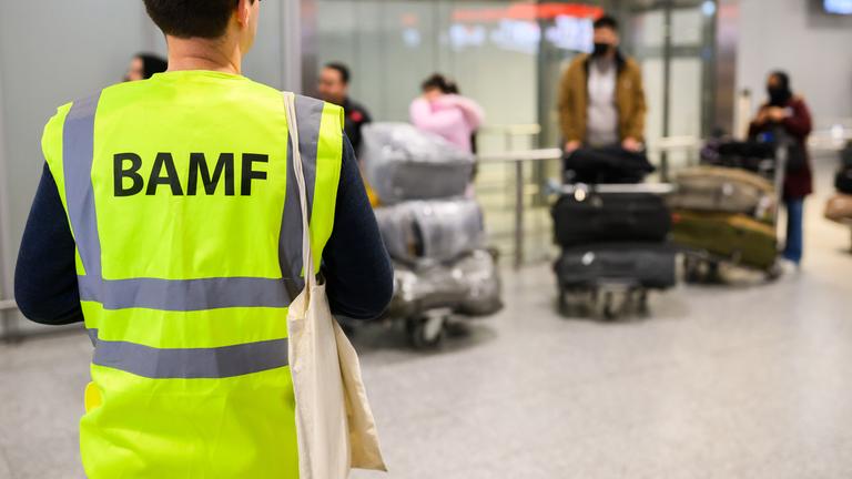 Ein Mitarbeiter vom BAMF Bundesamt für Migration und Flüchtlinge steht im Flughafen Hannover vor Afghaninnen und Afghanen aus den Bundesaufnahmeprogrammen. 