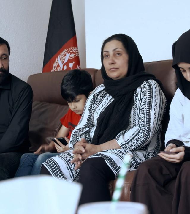 Vater, Sohn, Mutter und Tochter sitzen auf dem Sofa