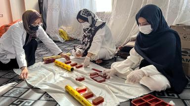 Rukia Resai (l) verpackt Seife mit ihren Schwestern in ihrer Seifenfabrik am 28.07.2026 in Herat, Afghanistan.