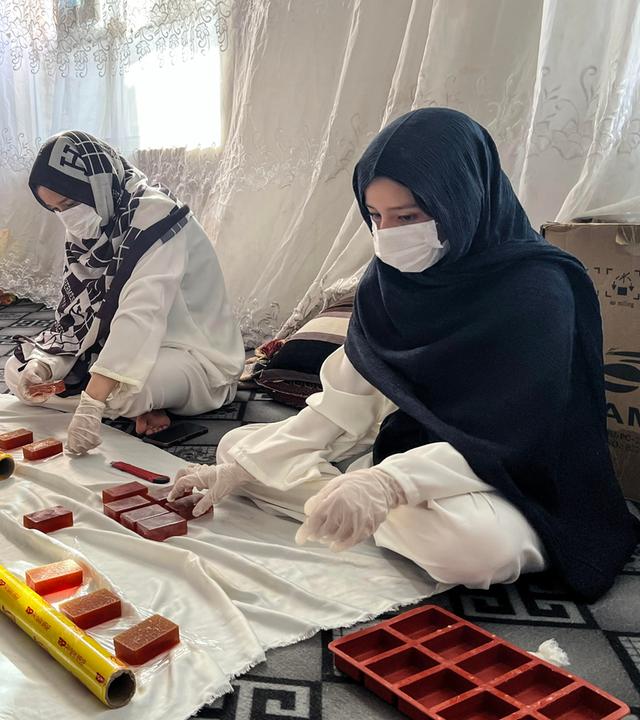 Rukia Resai (l) verpackt Seife mit ihren Schwestern in ihrer Seifenfabrik am 28.07.2026 in Herat, Afghanistan.