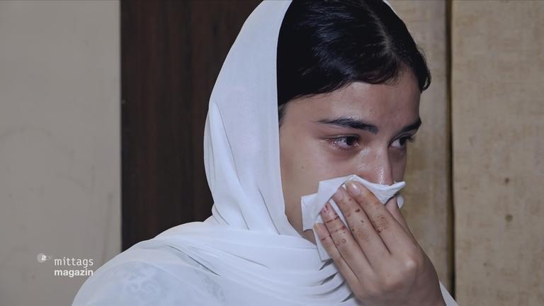 Frau mit Kopftuch sieht aus als würde sie weinen