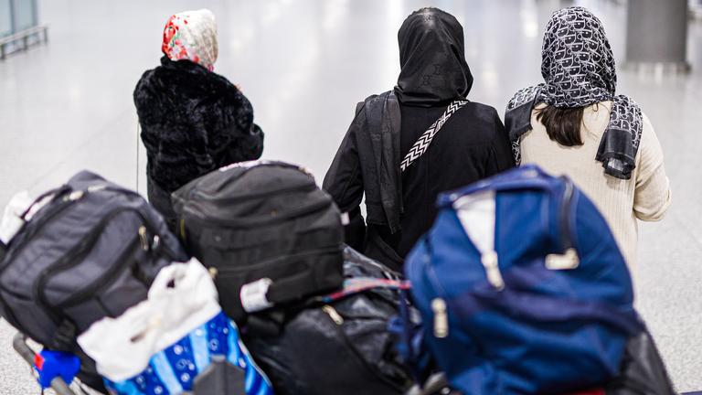 Menschen aus Afghanistan, die zuvor mit einem Flugzeug auf dem Flughafen Hannover-Langenhagen gelandet sind, verstauen ihr Gepäck in einem Anhänger. Die afghanische Staatsangehörige haben eine Aufnahmezusage für Deutschland.