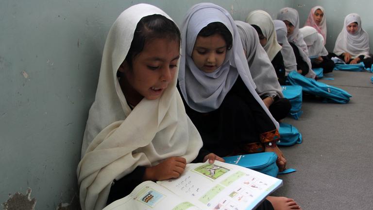 Afghanische Mädchen sitzen in einer Grundschule in Kandahar auf dem Boden.