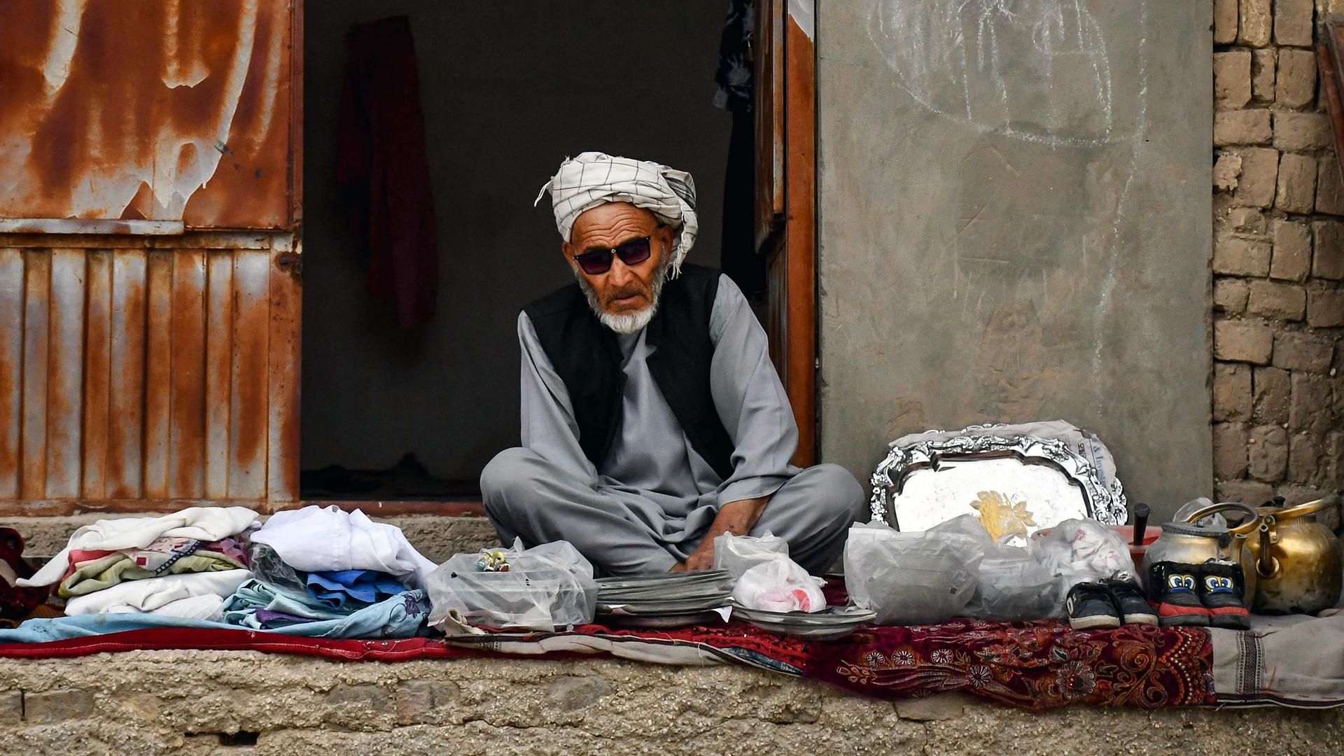 Ein afghanischer Mann, der an der Straße Kleidung verkauft, wartet auf Kunden.