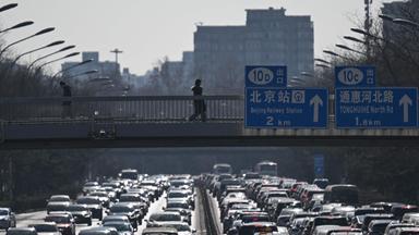 This picture taken on February 11, 2026 shows pedestrians walking along an overpass as traffic snarls in Beijing.