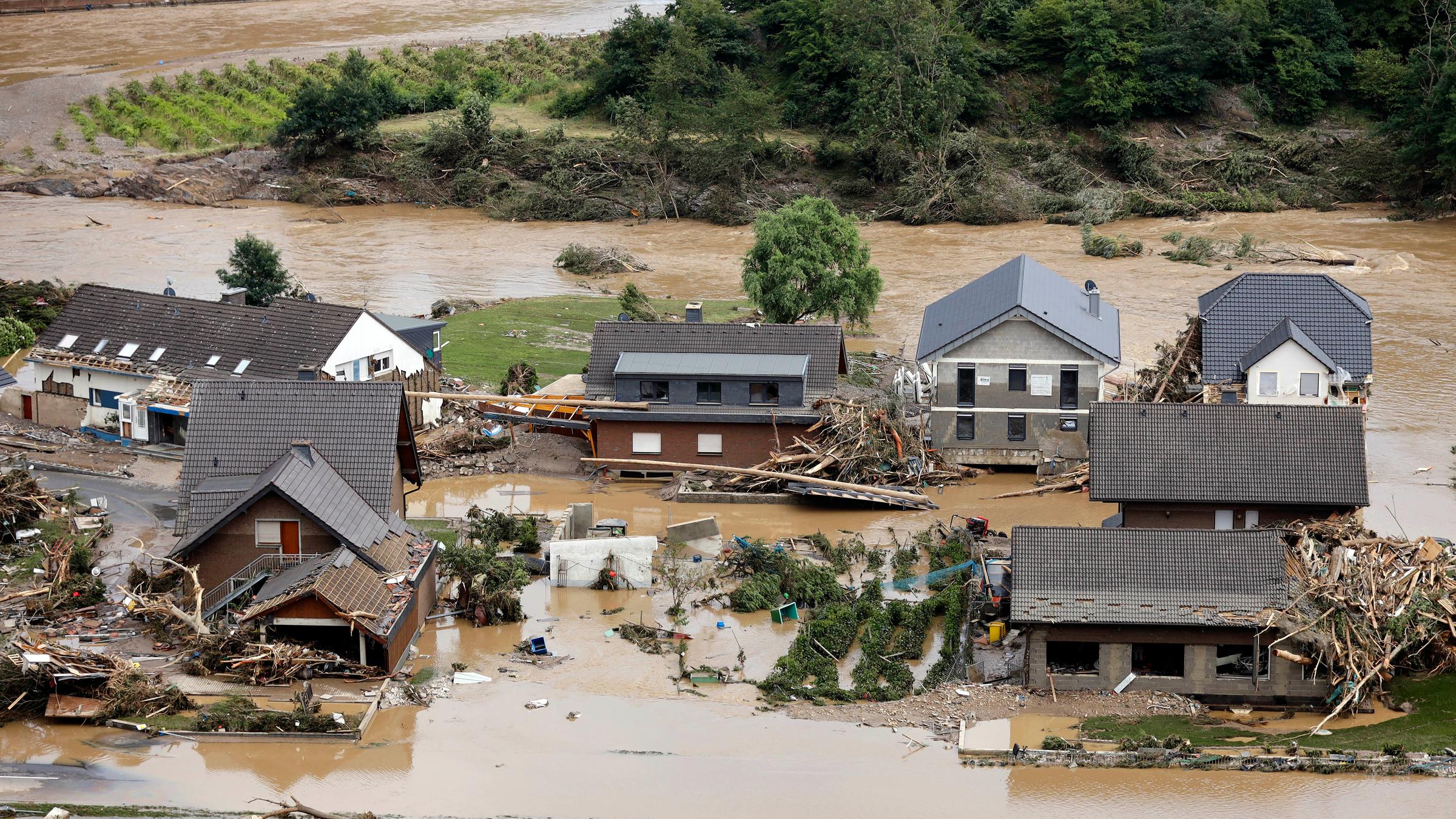 Ein Dorf ist überflutet, zwischen den Häusern liegen Schutthaufen und Schlamm.